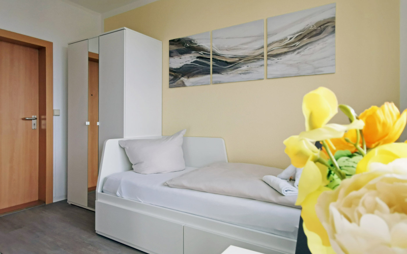 Helles Zimmer mit Bett, Wandbildern und Strauss Blumen