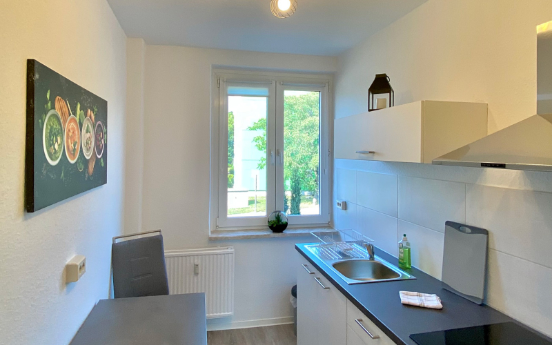 Moderne Küchenzeile mit Tisch, Stühlen und Wandbild