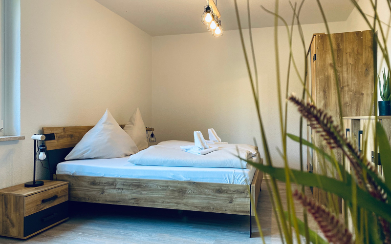 Gemütliches Schlafzimmer, Möble in Holzoptik, im Vordergrund Grünpflanzen